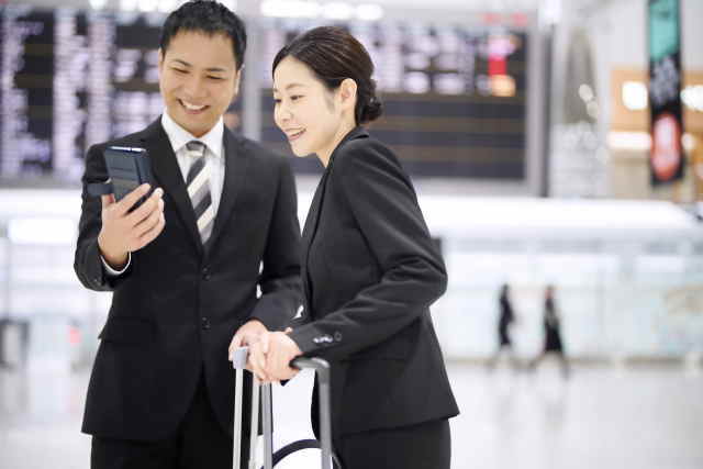 空港で仲良くスマホを一緒に見るカップル